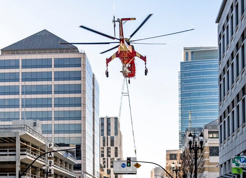 A Sikorsky Sky Crane helicopter carries a large air conditioning unit before dropping it onto Clay Street near 14th Street in downtown Oakland on Saturday Jan. 9, 2021. (Photo: Gabriel Tcruz)
