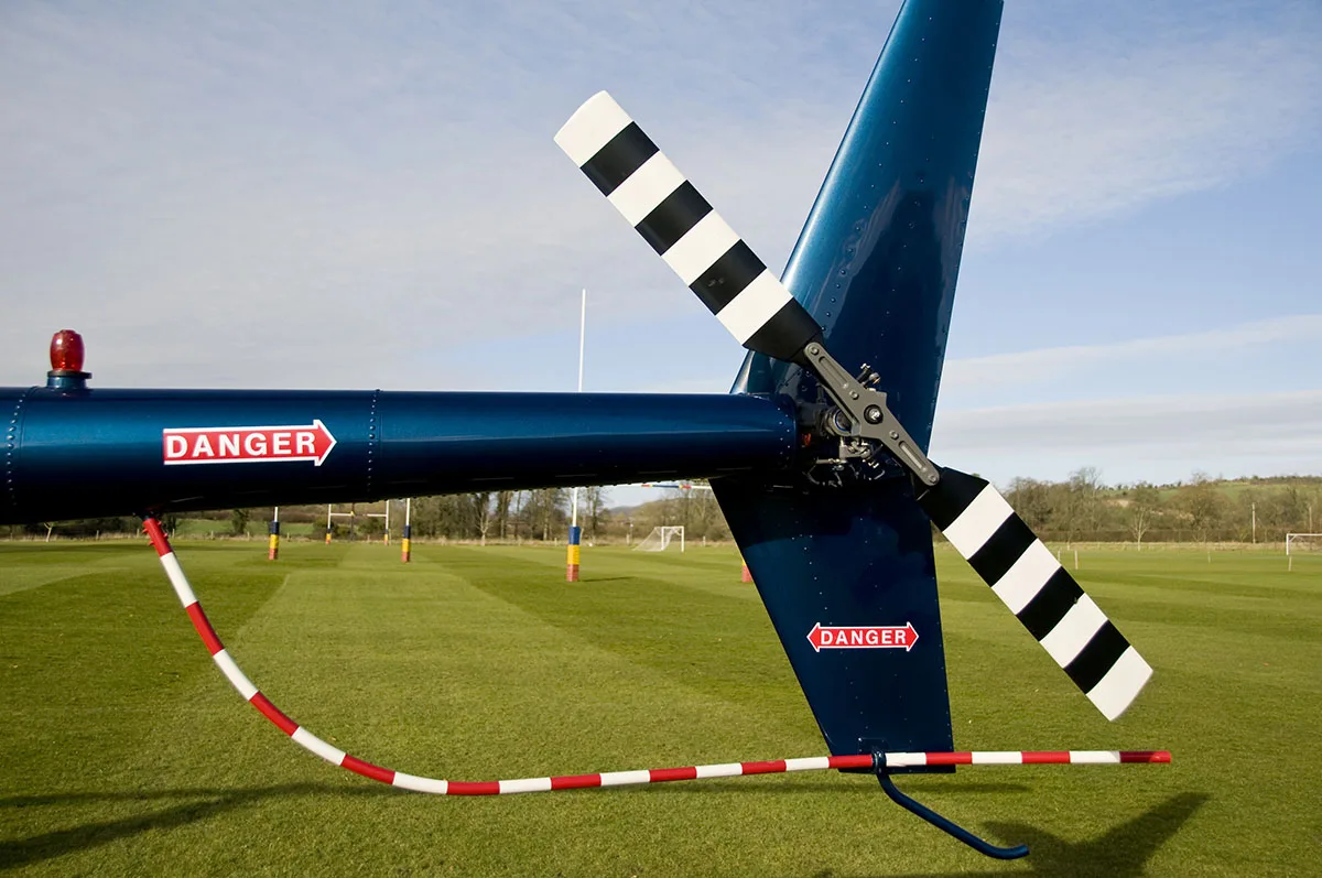 Helicopter tail rotor on a soccer field, demonstrating Fair Lifts Helicopter Services' innovative sports field drying process.