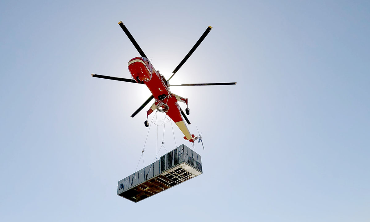 Sikorsky S-64E helicopter in flight, transporting a large RTU to its placement on the Seoyon E-Hwa plant roof via longline.