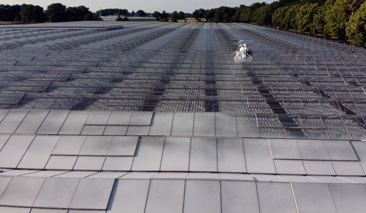 An XAG V40 drone coating a greenhouse with shading agent.