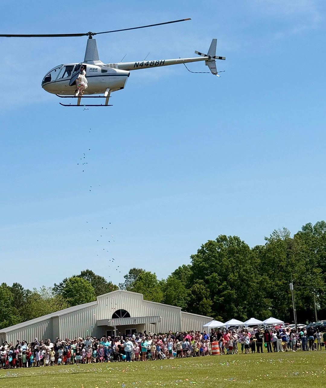 The churchgoers watch as 30,000 eggs are dropped from a Robinson R66 in Wrens, GA.