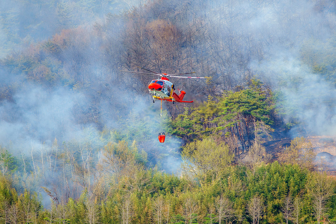 A Wildfire Helicopter battles a blaze with a Bambi bucket