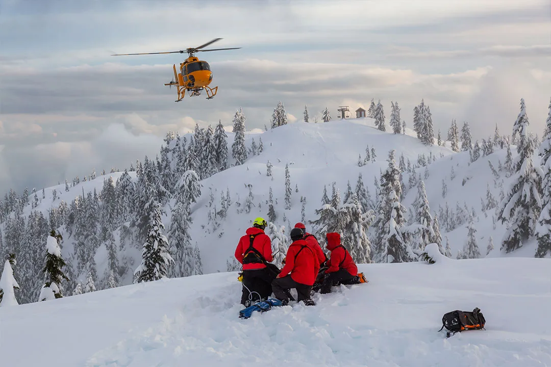 A rescue helicopter approaches in mountainous terrain.