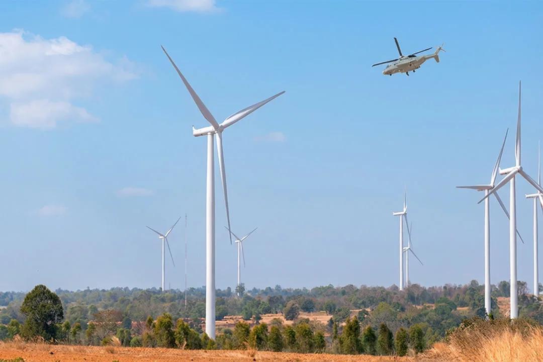 A helicopter surveys a wind farm.