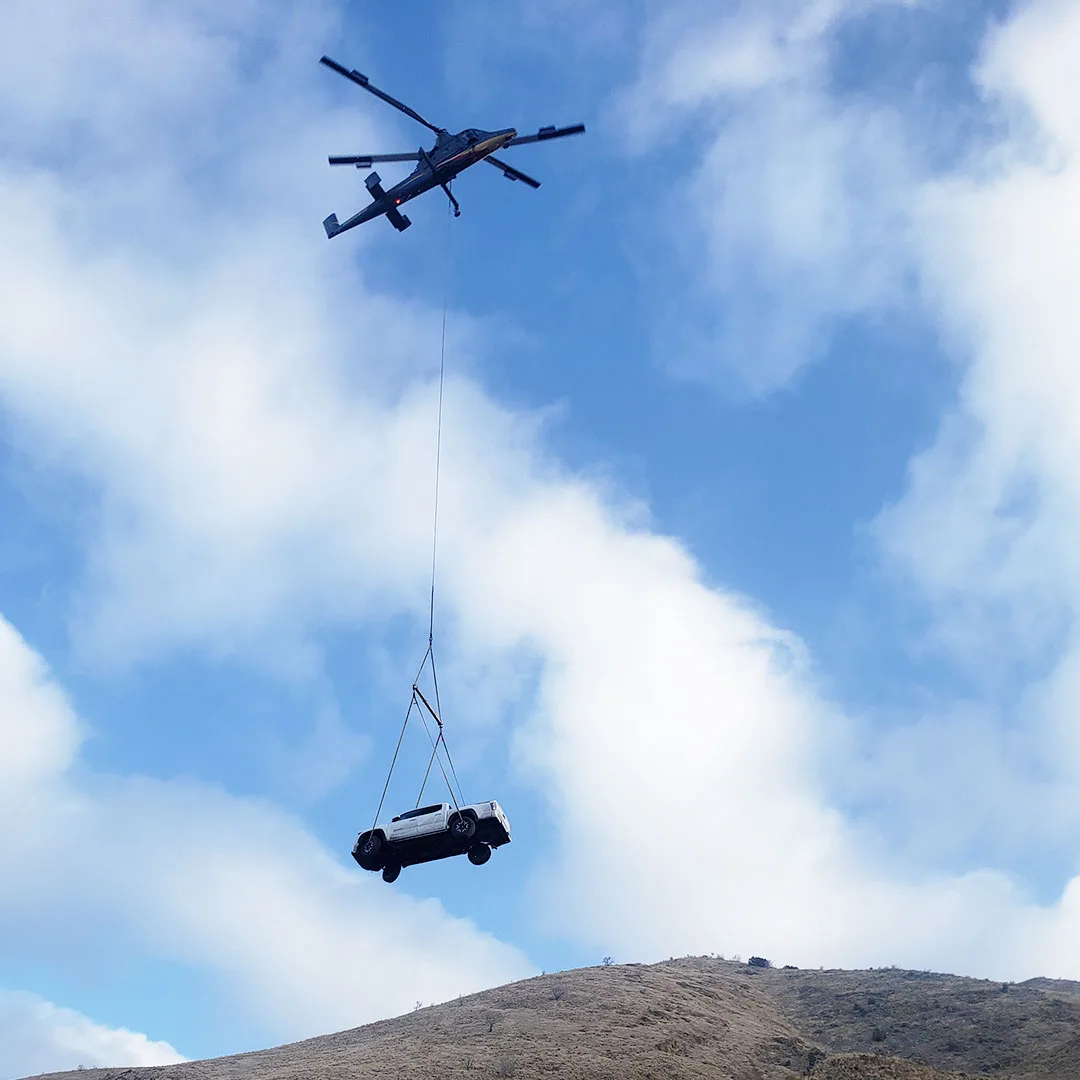 A successful aerial recovery mission using a Kaman K-MAX helicopter to extract and relocate a stranded Toyota Tacoma from a ravine.