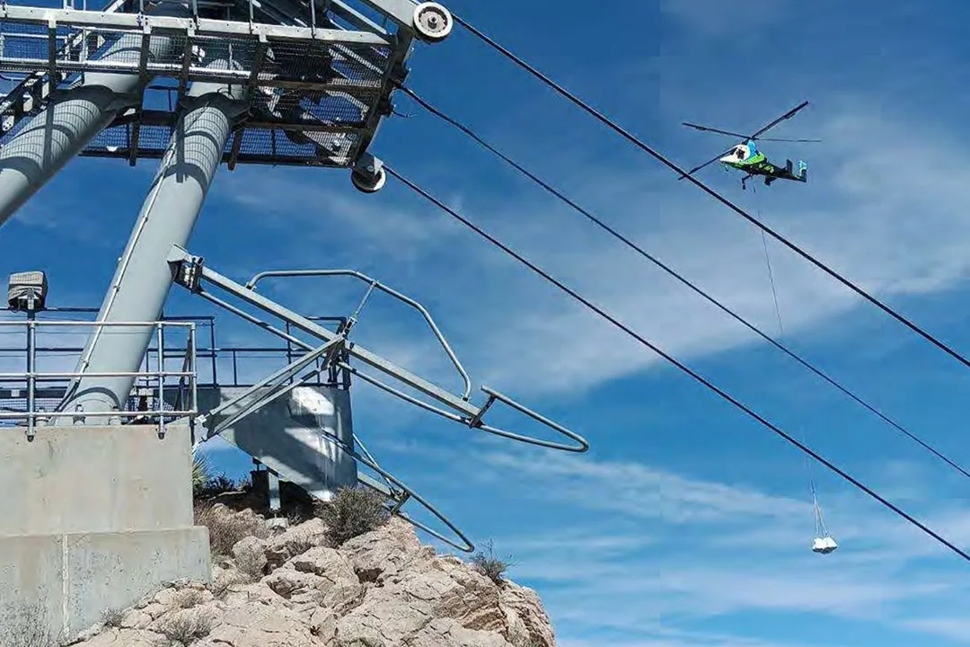 A K-MAX helicopter executes a long-line lift in a remote, mountainous location.