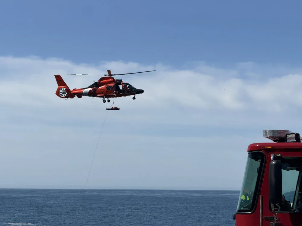 Suspended beneath the helicopter, the victim is carried to shore and transferred to a waiting ambulance for further care. | Photo: Depoe Bay Fire District