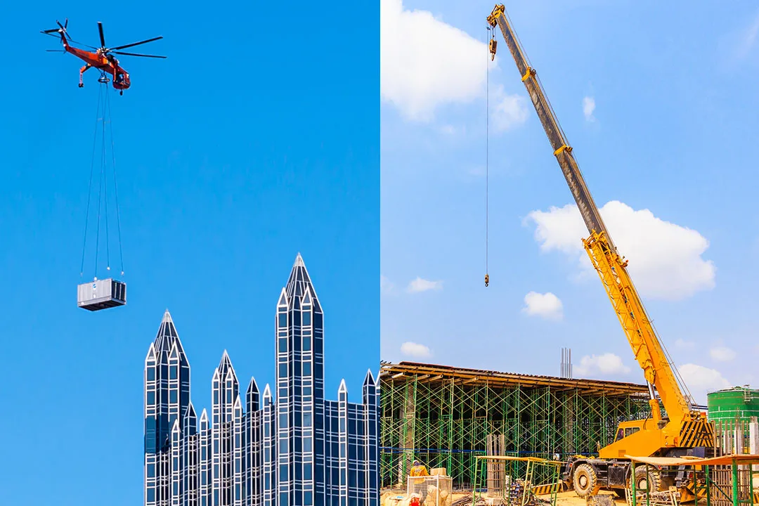 Helicopter lifting rooftop HVAC equipment beside a mobile crane operating at a construction site.