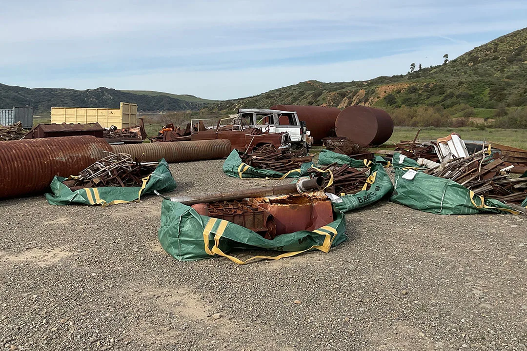 Construction equipment and materials positioned on rugged terrain at a remote worksite with limited ground access.